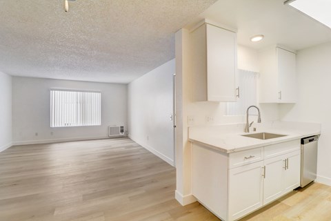 A kitchen with white cabinets and a wooden floor.