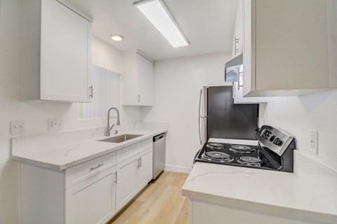 A kitchen with white cabinets and a black stove top oven.