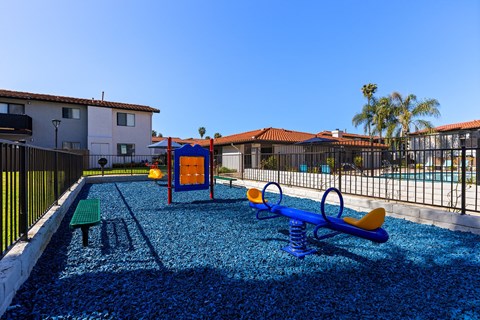 A playground with a blue slide and a yellow swing set.