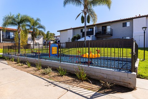 A pool surrounded by a black fence with a small orange boat in the water.