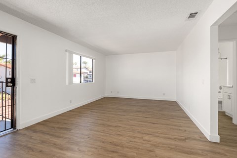 Empty room with wooden flooring and white walls.