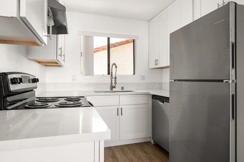A modern kitchen with a stainless steel refrigerator and white countertops.