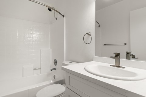 A white bathroom with a toilet, sink, and shower.