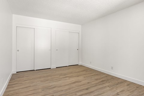 Three white doors in a room with wood flooring.