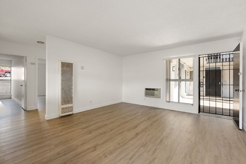 A spacious room with wooden floors and white walls.