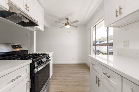 A white kitchen with a black stove top oven.