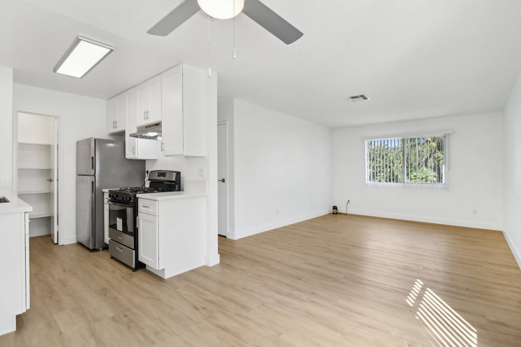 A spacious kitchen with white cabinets and a wooden floor.