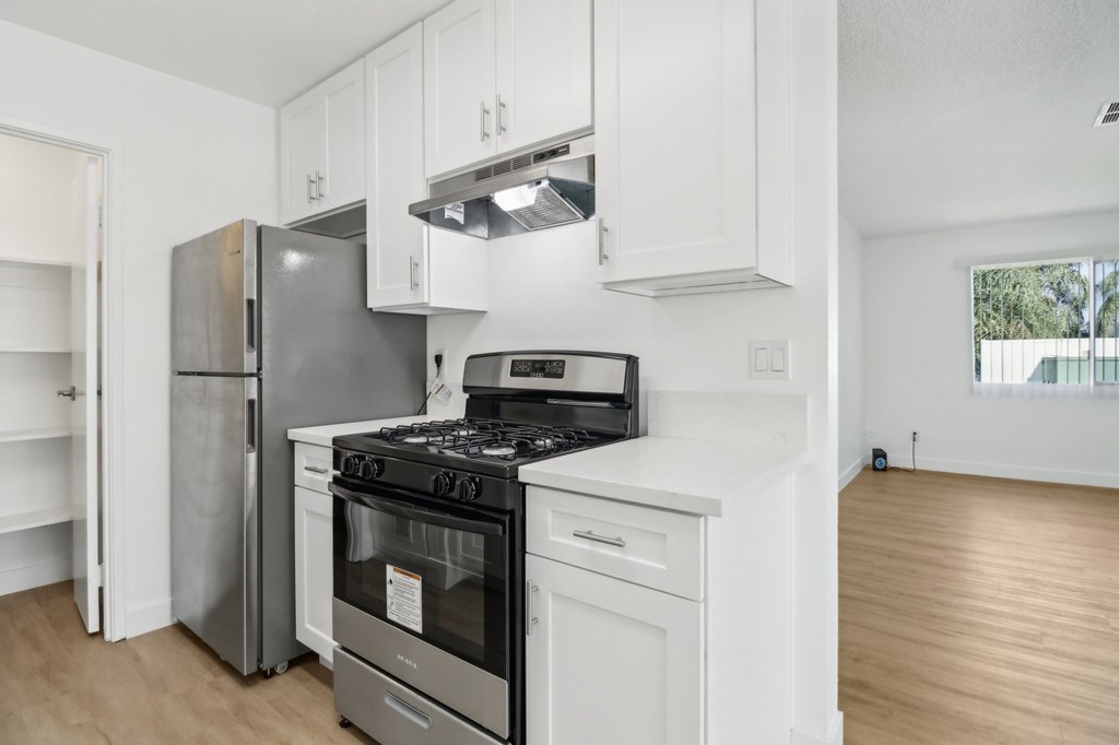 A modern kitchen with a stainless steel refrigerator, a white oven, and a black stove top.