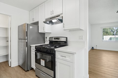 A modern kitchen with a stainless steel refrigerator, a white oven, and a black stove top.