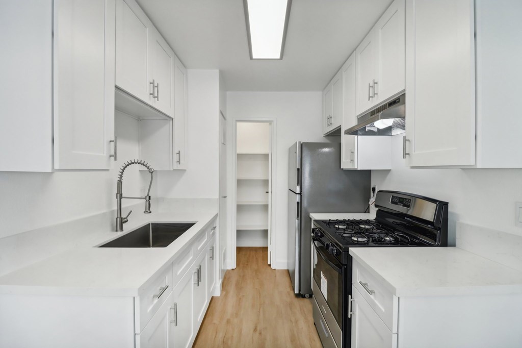 A kitchen with white cabinets and black appliances.