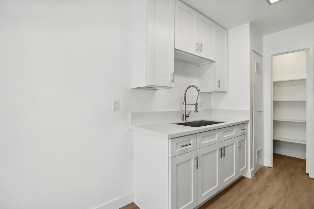 A white kitchen with a sink and cabinets.