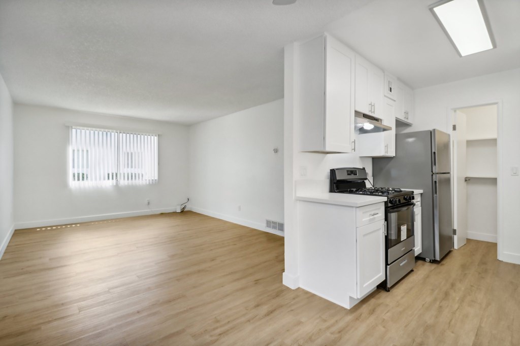 A kitchen with white appliances and wooden floors.