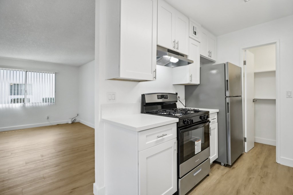 A white kitchen with a stove, oven, and refrigerator.