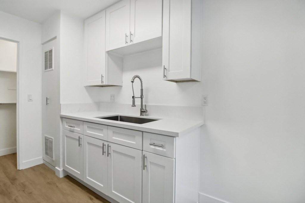 A white kitchen with a sink and cabinets.