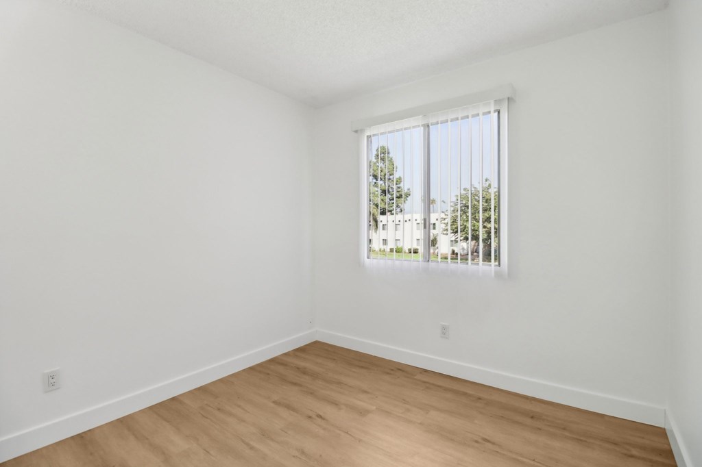 A room with a window and wooden flooring.