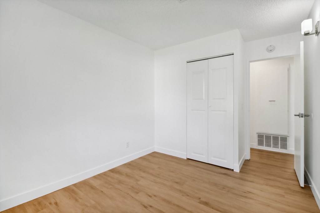 A white room with a wooden floor and a white door.