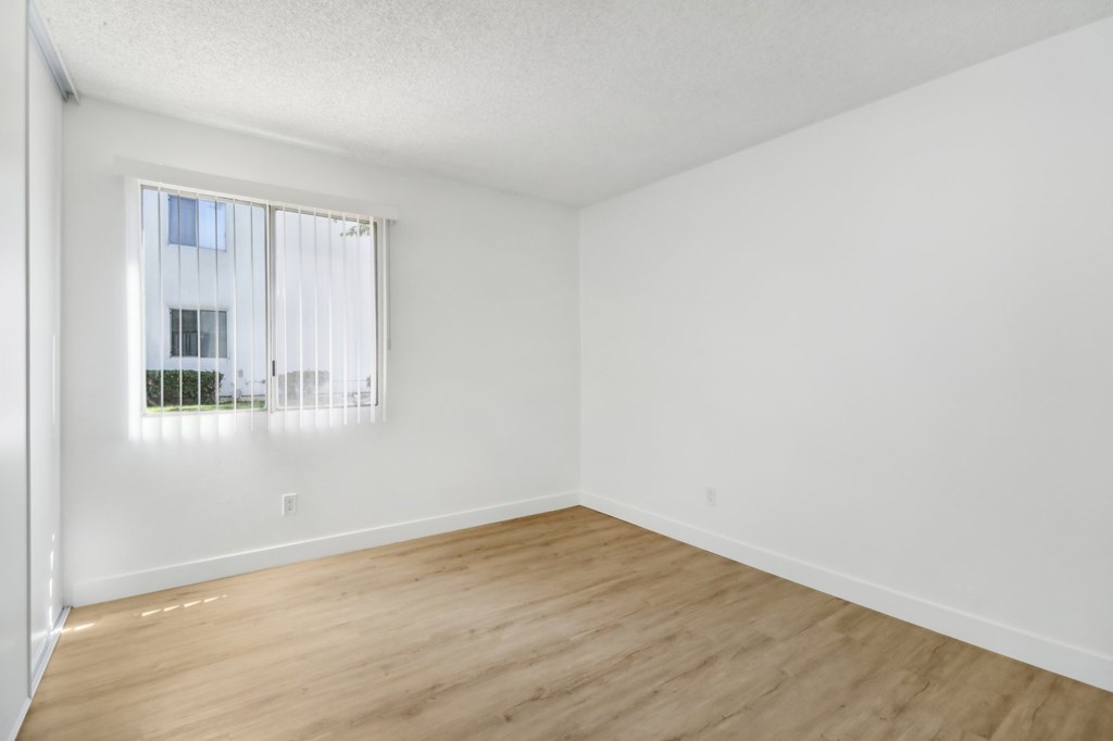A room with a window and wooden flooring.