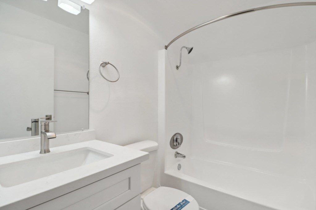 A white bathroom with a toilet, sink, and bathtub.