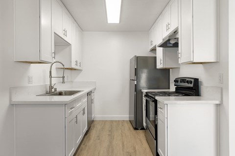 A kitchen with white cabinets and a black refrigerator.