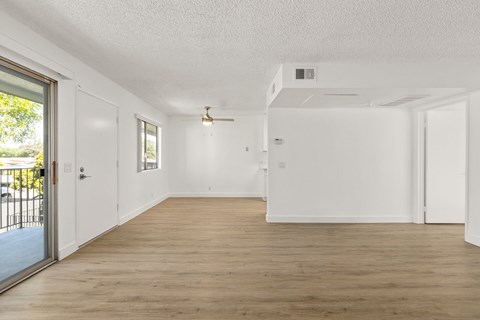 A spacious room with wooden flooring and white walls.