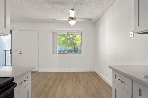 A kitchen with white cabinets and a window with a view of trees.