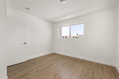 Empty room with a window and wooden flooring.
