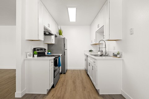 A kitchen with white cabinets and a wooden floor.
