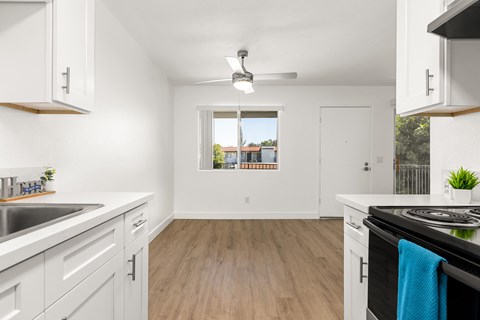 A kitchen with white cabinets and a wooden floor.