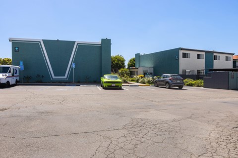 A green car is parked in front of a grey building.