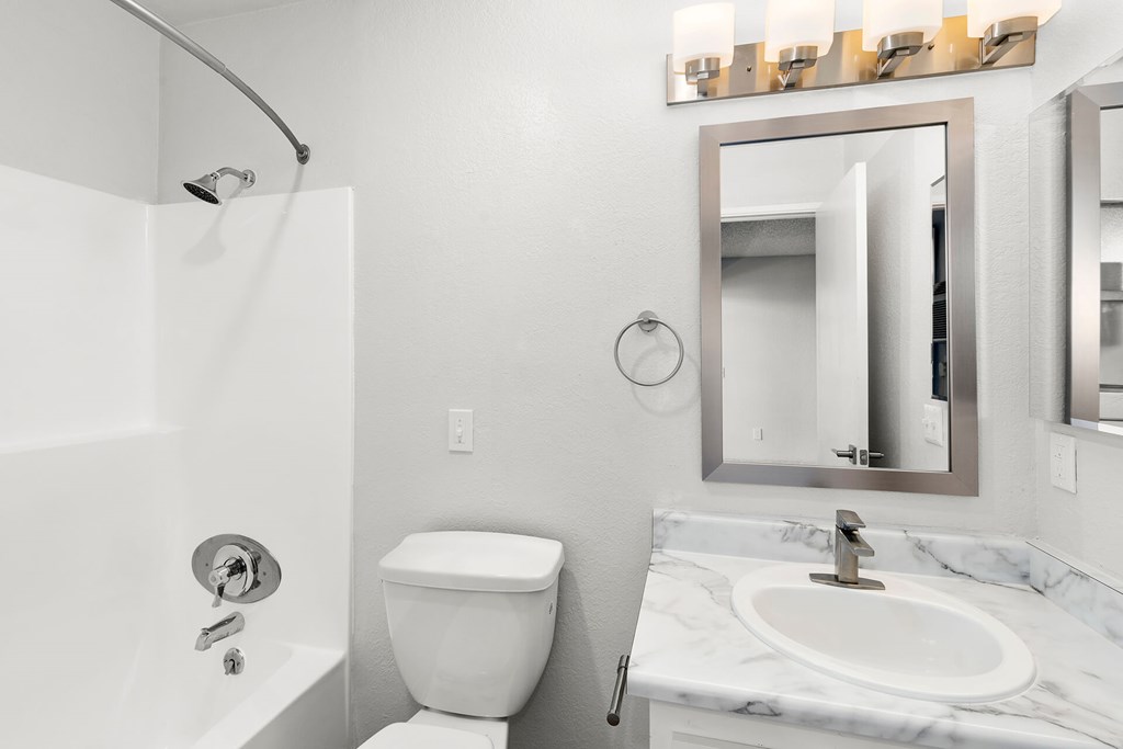 A white toilet sits next to a white sink in a bathroom.
