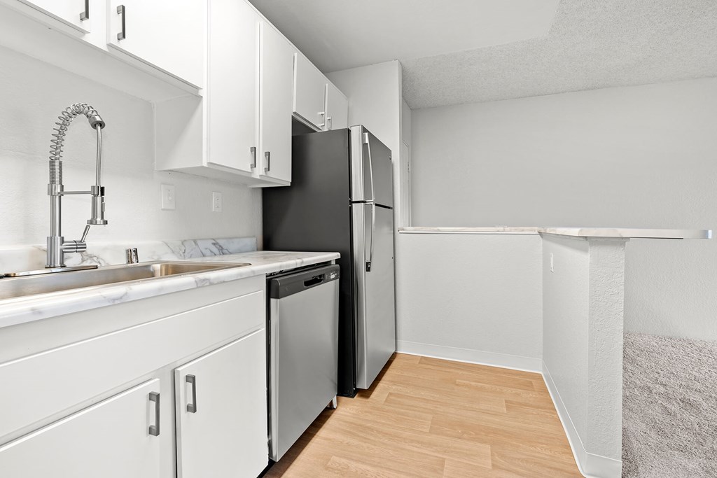 A kitchen with white cabinets and a black refrigerator.