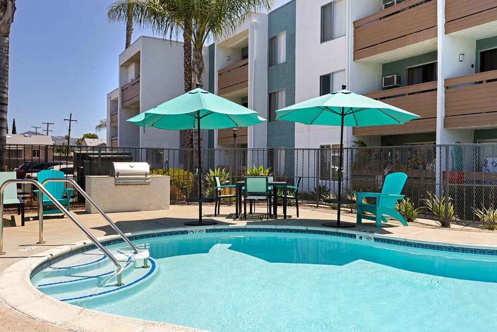 A pool with a slide and chairs with umbrellas.