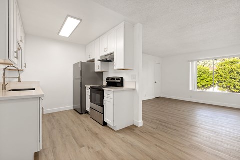 A kitchen with white cabinets and a wooden floor.