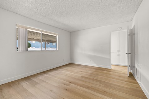 A room with a window and wooden flooring.