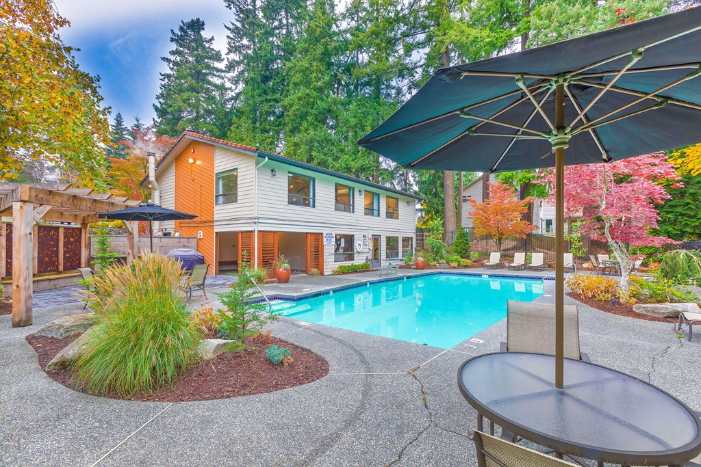 A pool with a table and chairs and a house in the background.