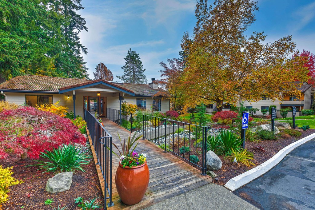 A building with a red roof and a wooden walkway leading to a gate.