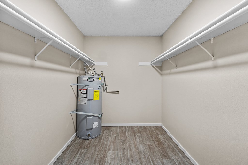 A utility room with a water heater and wood flooring.