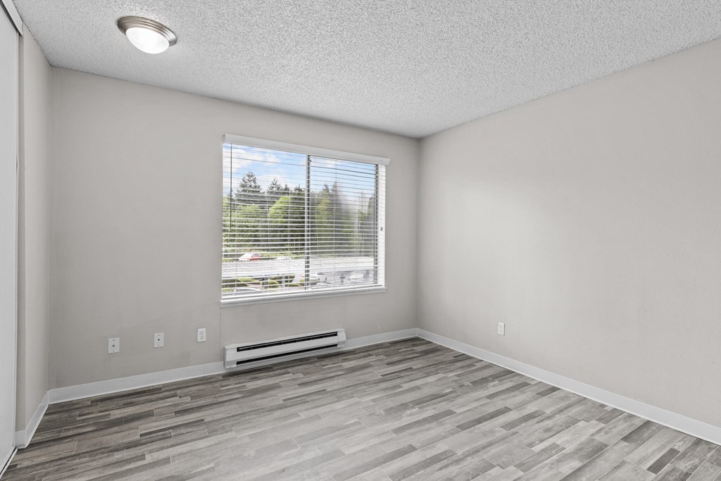 A room with a window and a wooden floor.