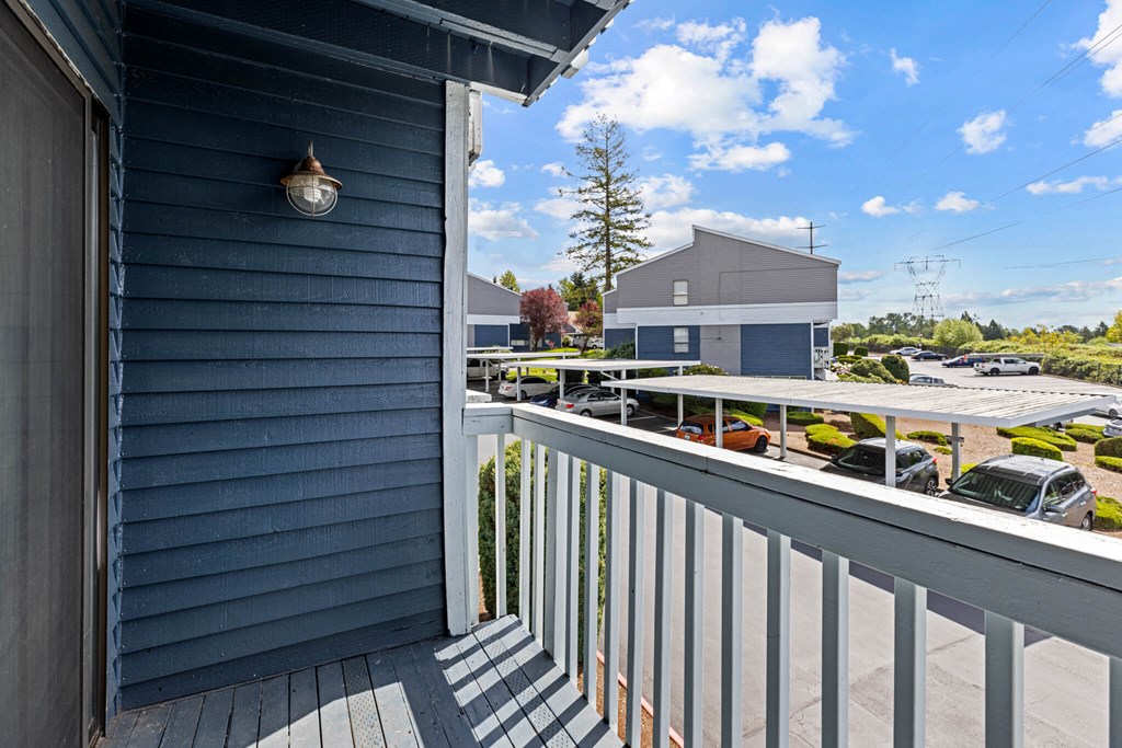 A balcony with a view of a parking lot and a building.