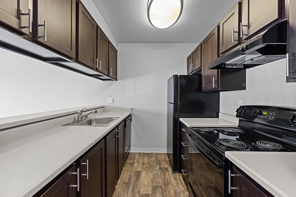 A kitchen with dark wood cabinets and black appliances.