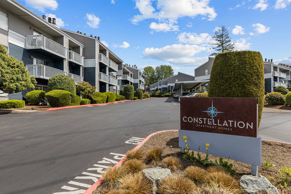 A sign for Constellation Apartments is in the foreground of a road.