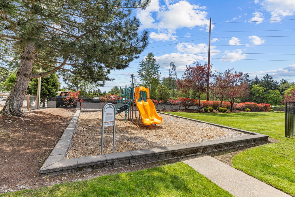 A playground with a yellow slide and a sign.
