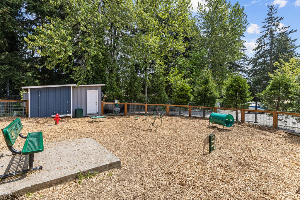 A playground with a green bench and a brown sandbox.