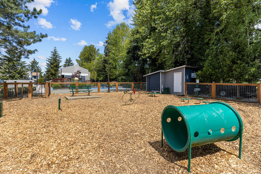 A playground with a green tube slide and a brown wooden fence.