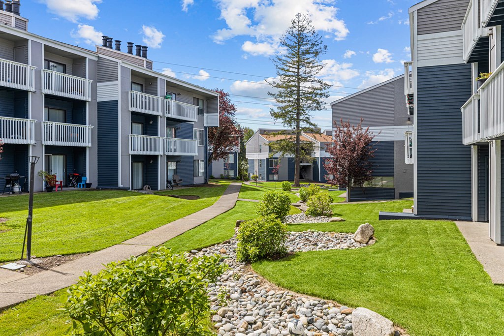 Apartment complex with a grassy area and a stone path.