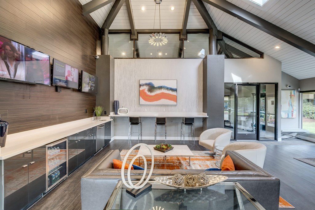 A modern kitchen with a glass table and a wooden ceiling.