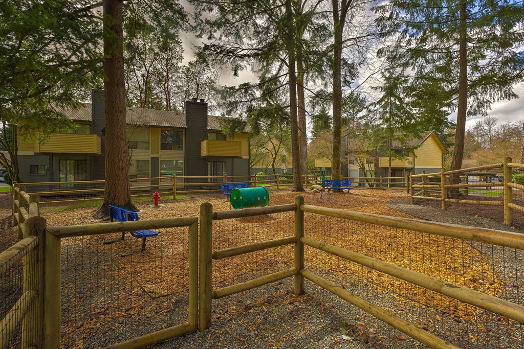 A playground with a wooden fence and a blue bench.
