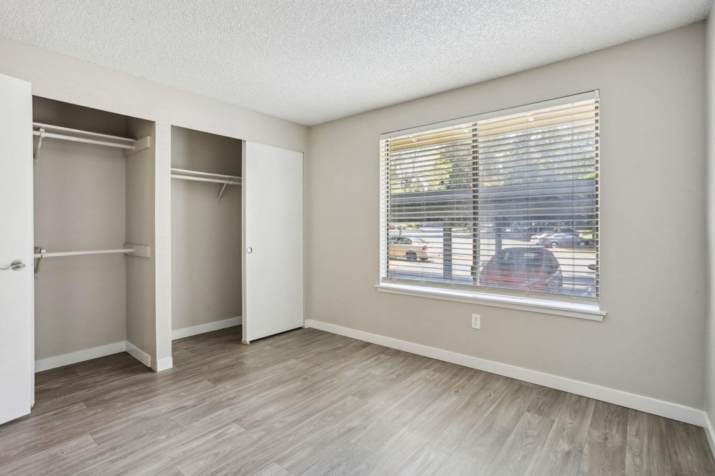 A room with a window and a view of a parking lot.