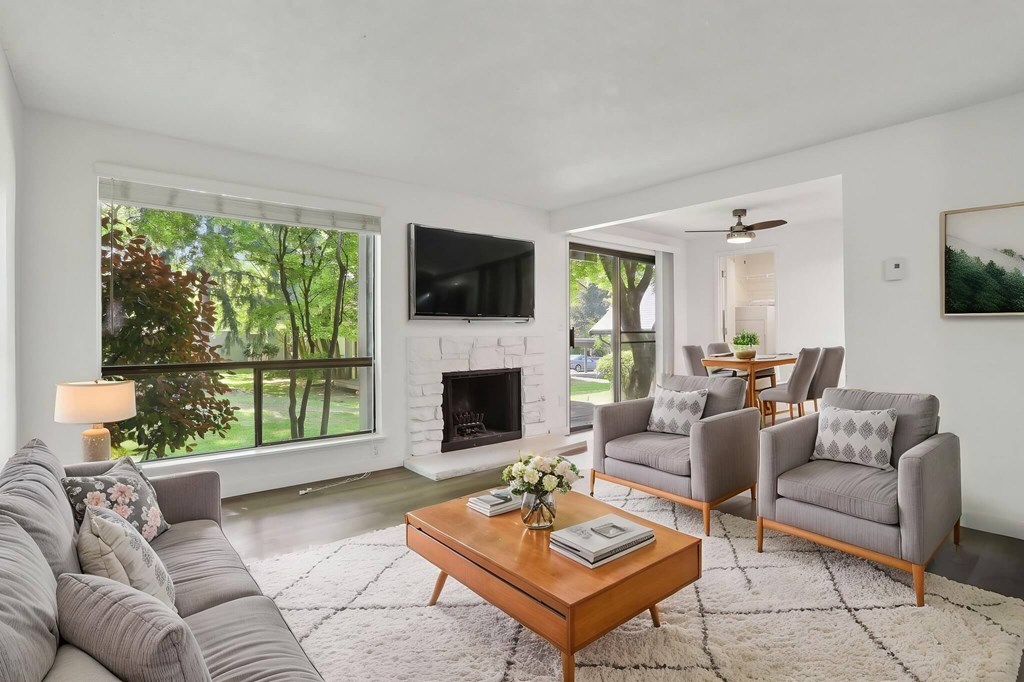 A living room with a grey couch, a wooden coffee table, and a flat screen TV mounted on the wall.