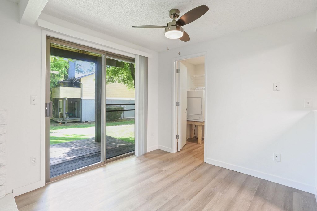 A room with a ceiling fan and sliding glass doors.